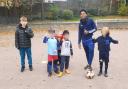 Oscar Lyons (left) with his football training group and Arsenal footballer Myles Lewis-Skelly (right) in Stationers Park