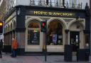A dispute over who would run The Hope pub theatre has resulted in the  management board resigning but landlords Greene King pledge it will continue to operate.