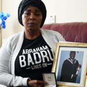 Ronke Badru, the mother of Abraham Badru who was shot dead in March 2018, holding a picture of her son and the bravery award he received in 2019