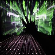 A zoom burst photo of a user touching the screen of a laptop displaying a 'Matrix'-style screensaver,