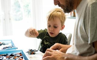 A young son builds Lego with his Dad at home